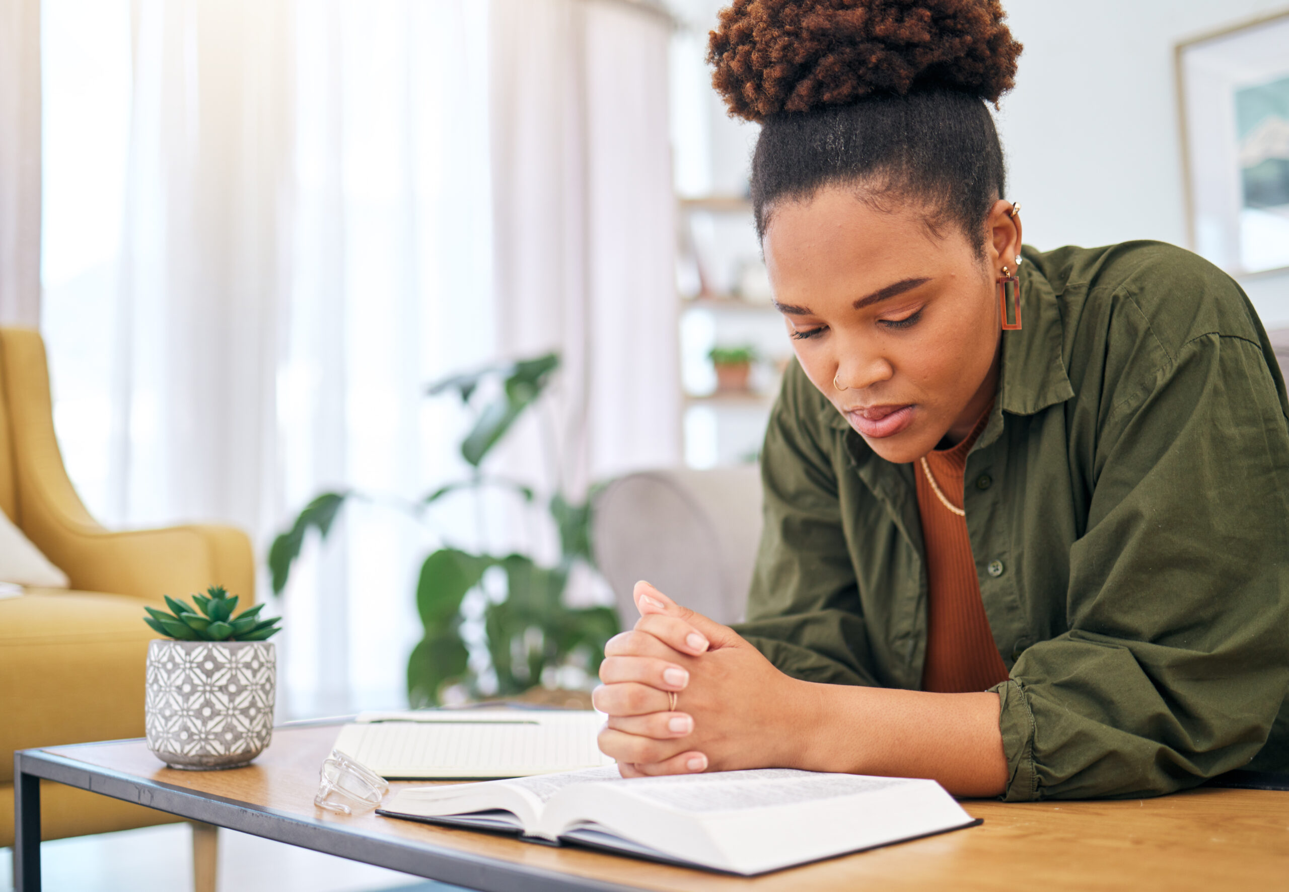 Young Woman, Bible And Prayer In Home, Desk And Mindfulness For Faith, Religion And Reading With Hope For Future. African Lady, Praying Hands And Study Holy Book For Peace, Meditation Or Worship God